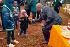 the-school-principal-maina-githenya-serving-anniversary-cake-to-children-visitors-on-1st-July-2022